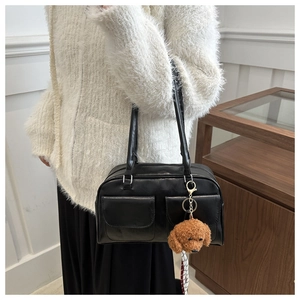 Détail du sac sous le bras noir avec poches à rabat et breloque en forme d'ourson