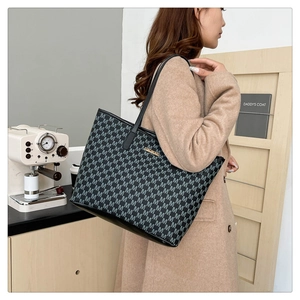 Détail d'un sac cabas noir vintage avec motif M et plaque métallique dorée décorative