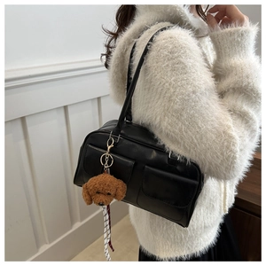 Detalle del bolso tote negro de cuero sintético con bolsillos cargo y amuleto de caniche