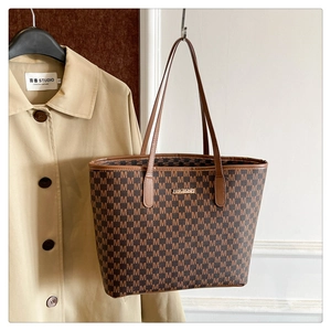 Detail of a brown tote bag with all-over M pattern and JINGPINPI metal logo nameplate