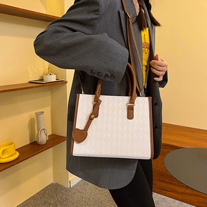 White quilted tote bag with brown straps and heart charm shown on a female model