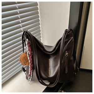 Dettaglio borsa shopper marrone in finta pelle con tracolla intrecciata e ciondolo orsetto