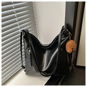 Dettaglio della borsa tote in pelle PU nera con cerniera laterale e ciondolo a forma di orso