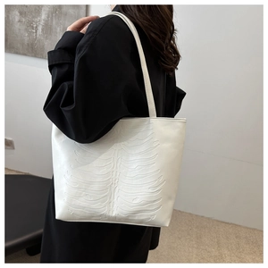 Detail of white leather tote bag featuring 3D embossed ribcage bone design and long straps