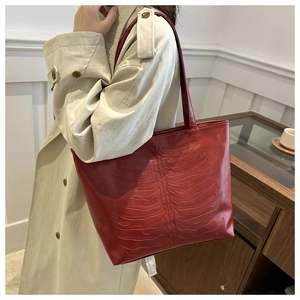 Detail of dark red tote bag featuring 3D skeleton rib cage embossed design on soft leather