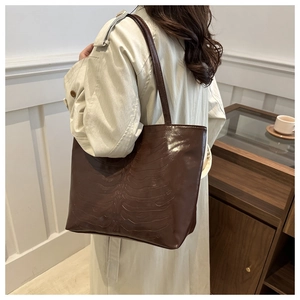 Detail of dark brown tote bag with unique bone pattern embossing on matte leather finish