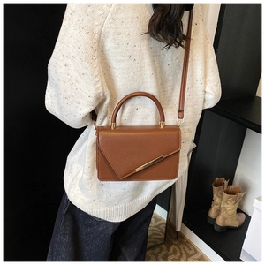 Caramel brown leather crossbody bag styled with a white sweater in a daily scene