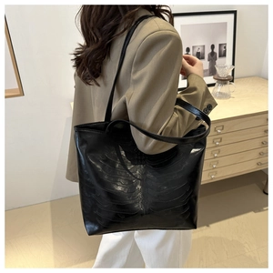 Detail of 3D embossed skeletal rib cage texture on a black glossy leather tote bag