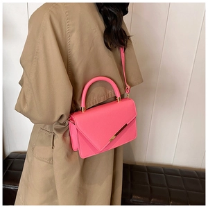 Close-up of vibrant pink lychee pattern leather bag with gold trim on a beige trench coat