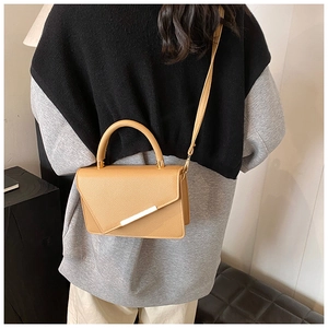 Detail view of khaki pebbled leather mini bag with asymmetrical flap and gold bar buckle