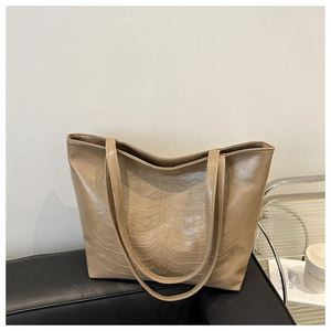 Detailed view of large khaki PU tote bag with unique bone-like embossed pattern on sofa