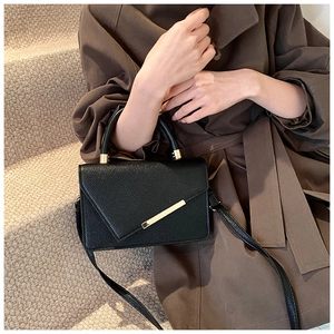 Chic black lychee texture crossbody bag with gold metal trim shown on a model
