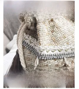 Dettaglio borsa a secchiello etnica in tweed con pizzo bianco e nappe marroni