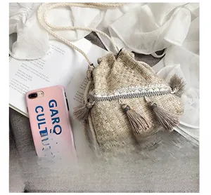 Dettaglio della borsa a secchiello in tweed con pizzo bianco, paillettes e nappe beige