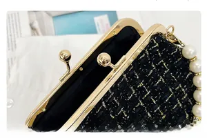 Close-up of black tweed texture with gold chain detail and pearl handle on bag