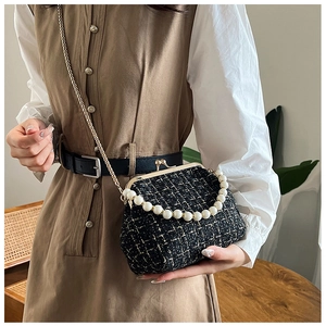 Close-up of black and white tweed shell bag with pearl handle and gold chain strap