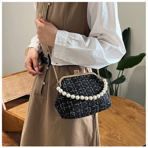 Detail of tweed shell bag with pearl handle and golden chain strap in a lifestyle setting
