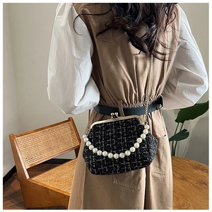 Detail of tweed crossbody bag with pearl strap and gold clasp on a model indoors