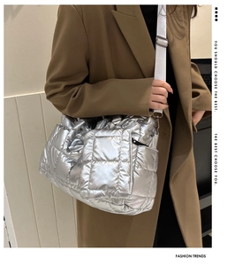 Detail of silver quilted puffer bag with metallic finish and wide woven shoulder strap