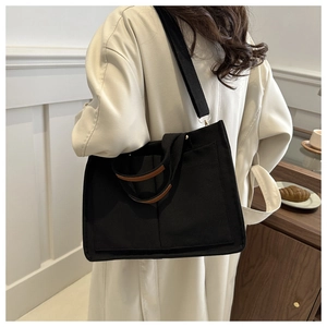 Grand sac cabas en toile noire avec garniture marron, porté à l'épaule, style minimaliste