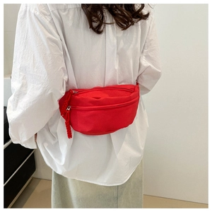 Detail view of a bright red fabric chest bag featuring double zippers and woven drawstrings