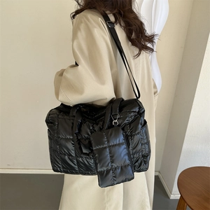 Sac fourre-tout matelassé et pochette sur un mannequin portant un manteau beige
