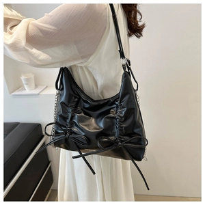 Detail of black pleated shoulder bag with bows and silver metal chain strap leather