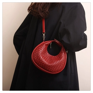 Dettaglio borsa a mezzaluna in pelle intrecciata rossa con tracolla e fibbie d'oro