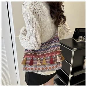 Dettaglio della borsa a tracolla intrecciata boho con nappe colorate e motivi geometrici