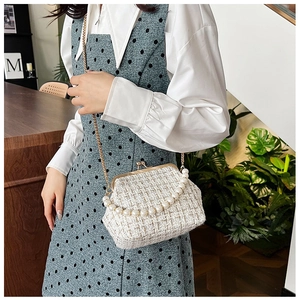 Detail of white wool tweed chain bag with pearl handle and golden clasp closure