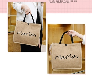 Detail of jute tote bag featuring black 'mama' print and woven handles on a shelf