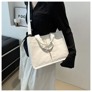 Détail du sac fourre-tout en toile blanc cassé avec poches avant et large bandoulière