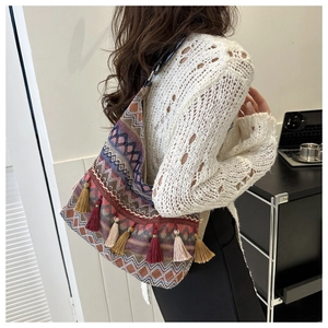 Dettaglio della borsa tote boho con motivi geometrici colorati e nappe decorative