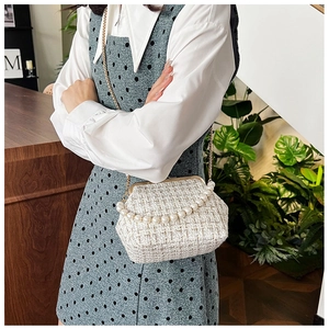 Detail of knit tweed shell bag featuring pearl handle and gold chain shoulder strap
