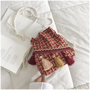 Dettaglio della borsa a secchiello in tweed rosso e bianco con nappe colorate e tracolla