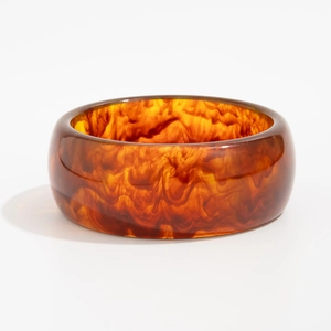 Bracciale rigido largo in resina ambrata con texture marmorizzata da donna, vista 45 gradi