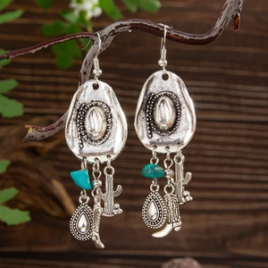 Detail of vintage silver western earrings with turquoise, cactus, and cowboy boot charms