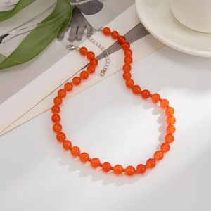 Detail van doorschijnende oranje glazen kralenketting met zilveren karabijnsluiting