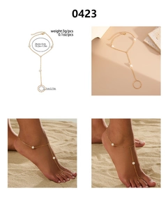 Chaîne de jambe dorée ajustable avec bague d'orteil et perles blanches sur la plage