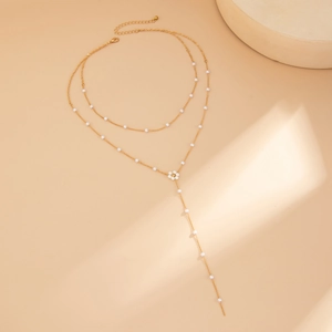 Dettaglio della collana dorata a due strati con fiori di perle e pendente a forma di Y