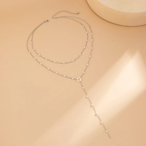 Dettaglio della collana a Y argentata con perle delicate e ciondolo a fiore