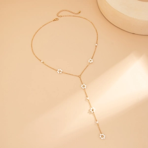 Dettaglio della collana a Y dorata con delicati fiori di perle e nappine eleganti