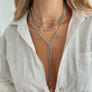 Dettaglio collana lariat a Y argentata con perline e ciondolo a goccia in metallo