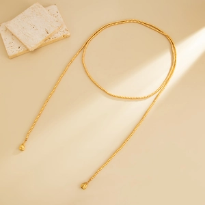 Dettaglio della collana di perline dorate con eleganti ciondoli a goccia lucidi