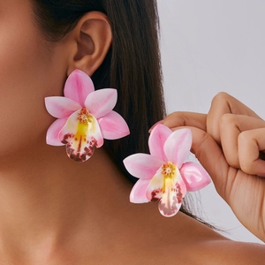 Close-up of pink orchid floral earrings with yellow centers on a fashion model