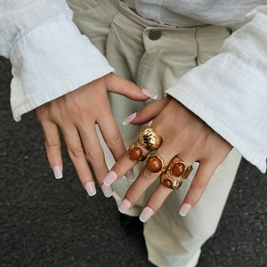 Detail of 5-piece retro ring set with amber acrylic stones and gold hammered metal finish