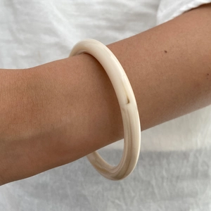 Dettaglio di un bracciale geometrico in resina crema indossato sull'avambraccio