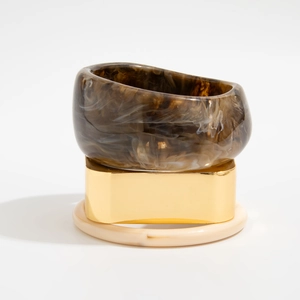 Dettaglio del set di bracciali in resina e lega dorata con eleganti trame marmorizzate