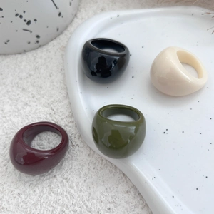 Close-up of four minimalist thick resin rings in burgundy, olive green, black and ivory