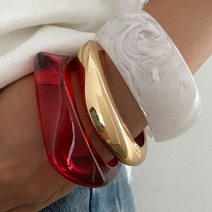 Set di tre bracciali in resina rossa, metallo dorato e marmo indossati da una modella